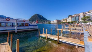 Una costa despejada con un muelle, un barco y una montaña al fondo.