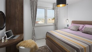 A bedroom with a bed, a desk with a laptop, a window with curtains, and a view of the outside. - Apartments Vista Exclusive  (Vir)