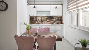 A modern kitchen with white cabinets, a wooden countertop, and pendant lighting. - Apartments Vista Exclusive  (Vir)