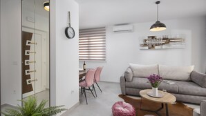 A modern living room with a sofa, a coffee table, a dining area with chairs, and a potted plant. - Apartments Vista Exclusive  (Vir)