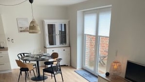 Una sala de estar moderna con un sofá, una mesa de centro de vidrio y un televisor sobre un mueble de madera.