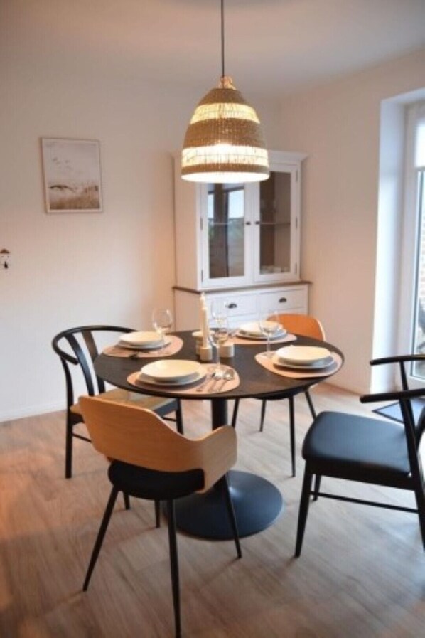 Een eetgedeelte met een ronde tafel, zwarte stoelen en een hangende lamp.