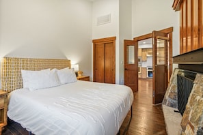 A bedroom with a large bed, wooden wardrobe, and a stone fireplace.