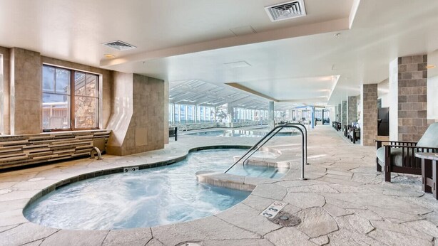 A spa area with a hot tub, stone flooring, and a view of the outdoors.