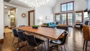 A spacious living room with a large wooden dining table, comfortable seating, and a view of the outdoors.