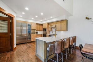 Una cocina moderna con armarios de madera, electrodomésticos de acero inoxidable y una isla central con taburetes de bar.