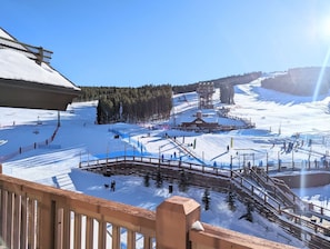 Un centro de esquí con una ladera cubierta de nieve, un telesilla y una valla de madera.