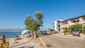 A beachside view with a building, a clear sky, and a calm sea. - Apartment Nada (Vir)