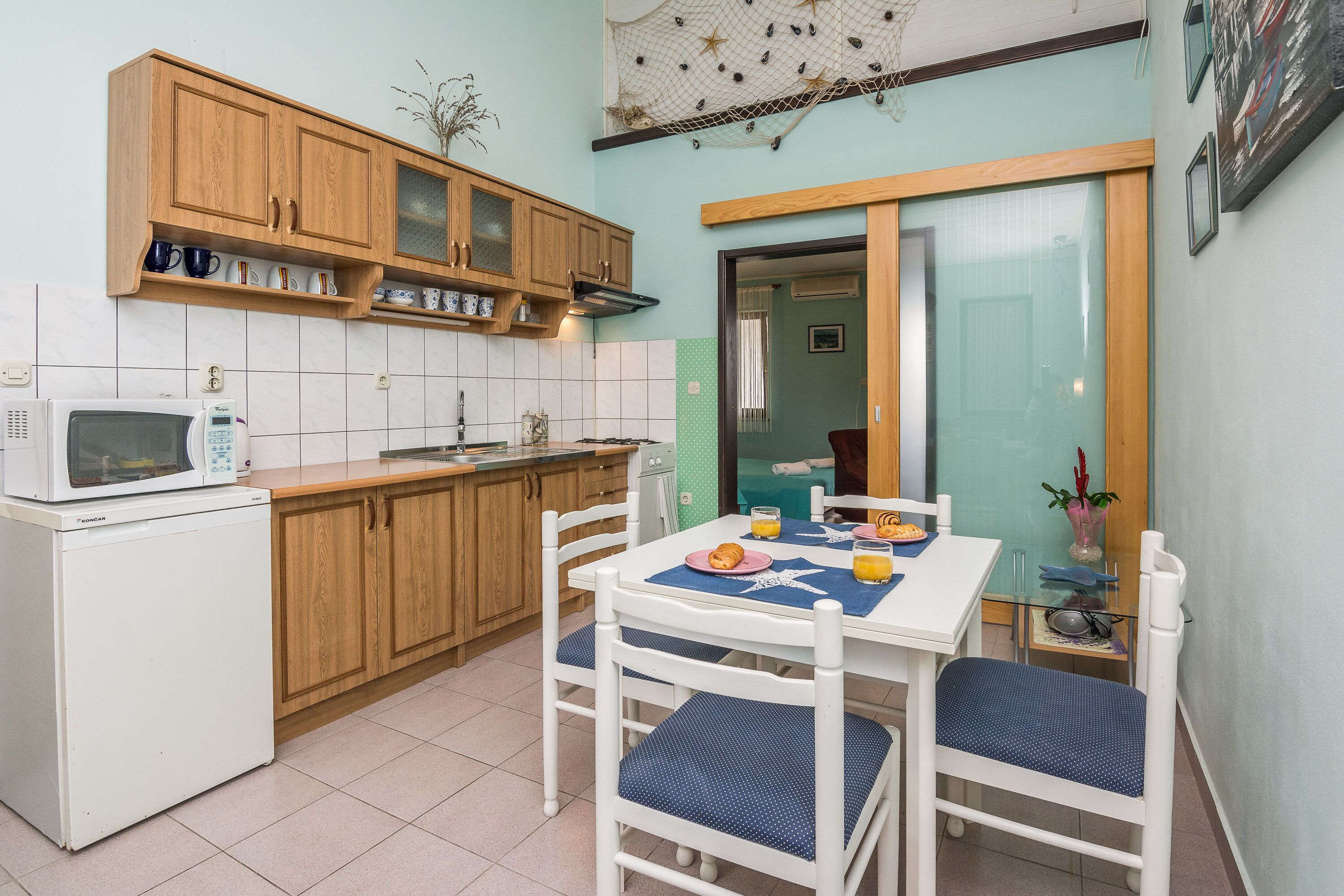 A compact kitchen with wooden cabinets, a microwave, and a dining table with chairs.