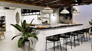 A modern kitchen with a marble countertop, black chairs, and hanging pendant lights. - Cretan Seaside Boutique Hotel (Hersonissos)