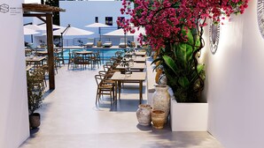 A poolside area with tables and chairs, a large potted plant, and a view of the pool. - Cretan Seaside Boutique Hotel (Hersonissos)