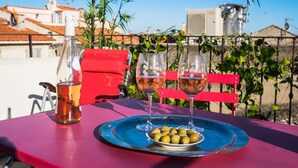 A table with a bottle, two glasses, and a plate of olives.
