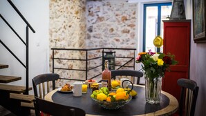 A dining table with a fruit bowl, a bottle, and a vase of flowers.