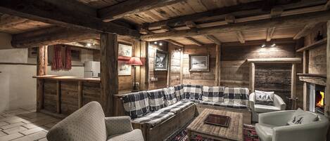 Interior acogedor de una cabaña de madera con un sofá a cuadros, una mesa de centro de madera y una chimenea.
