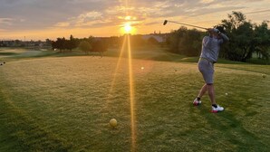 Un campo de golf con un atardecer de fondo.