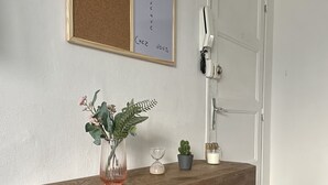 A wooden console table with metal legs, a corkboard with handwritten text, a potted plant, an hourglass, and a small cactus. - Bright, open-plan apartment (Montauban)