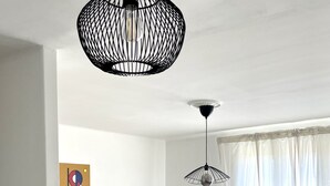 A modern living room with a grey sofa, a wooden coffee table, and two hanging pendant lights. - Bright, open-plan apartment (Montauban)