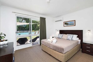 Una camera da letto con un letto, una scrivania, una sedia, una finestra vista piscina e un quadro appeso al muro.
