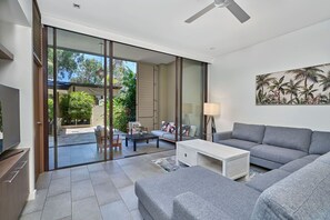 Relax in this stylish living room with a sofa, side table, and ceiling fan, offering a comfortable space to unwind.