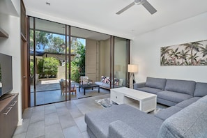 Relax in this stylish living room with a sofa, side table, and ceiling fan, offering a comfortable space to unwind.