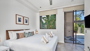 Une chambre moderne avec un grand lit, une table de chevet, un téléviseur fixé au mur et une fenêtre donnant sur un paysage verdoyant.