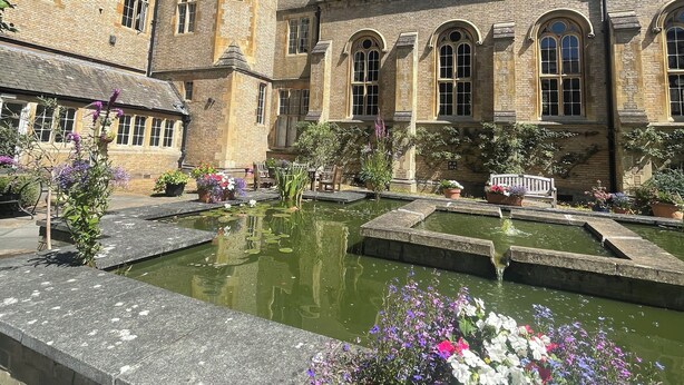 A historic building with a courtyard, including a pond and flower planters. - Stylish two-bedroom condo with free parking. (London)