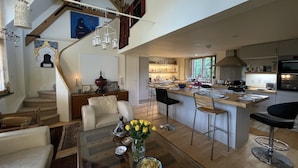 A spacious living area with a high ceiling, a kitchen with modern appliances, and a dining area with bar stools. - Stylish two-bedroom condo with free parking. (London)