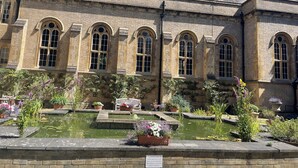 A historic building with arched windows and a courtyard with a pond and potted plants. - Stylish two-bedroom condo with free parking. (London)