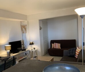 A living room with a TV, lamp, and sofa. - IN HOUSE SEA VIEW & ON ILE ROUSSE : T3 /4 PERS. TERRACE/CLIM BEACH 800m away (L'Île-Rousse)