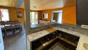 Una cocina moderna con techo de madera, un comedor con mesa y sillas, y vistas al exterior.