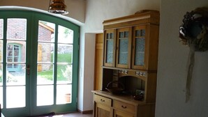 Une cuisine avec des meubles de rangement en bois et une porte verte donnant sur un jardin.