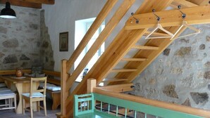 Un intérieur rustique avec un escalier en bois, un banc vert et des murs en pierre.