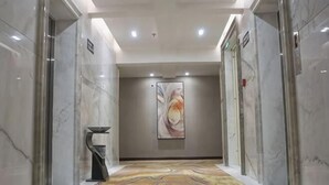 A hallway with marble walls, a patterned carpet, and a large abstract painting on the wall.