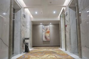 A hallway with marble walls, a patterned carpet, and a large abstract painting on the wall.