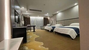 A hotel room with two beds, a desk, and a chair.