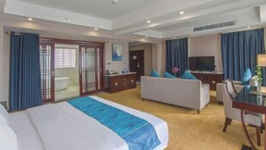 A hotel room with a bed, sofa, TV, and a desk with a chair.