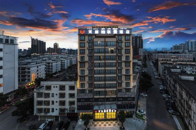 A multi-story hotel with a prominent sign at the top, surrounded by other buildings.