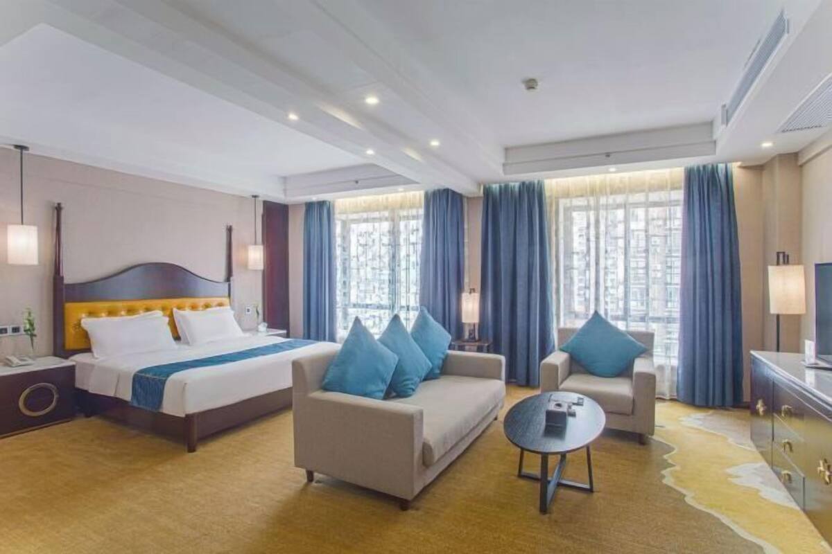 A hotel room with a bed, two sofas, a coffee table, and a desk.