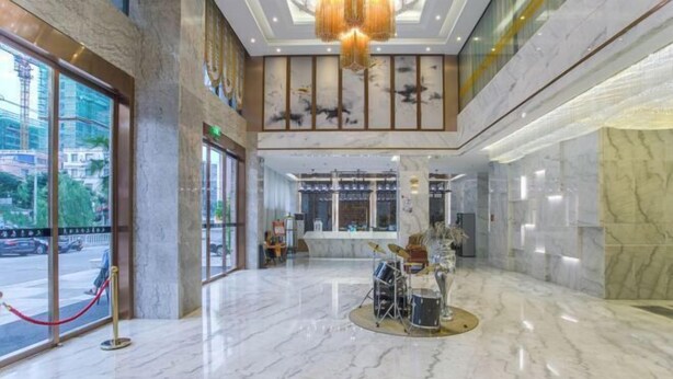 A spacious lobby with a marble floor, a drum set, and a large chandelier.