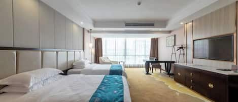 Quarto de hotel com duas camas, uma escrivaninha, uma televisão e uma janela grande.