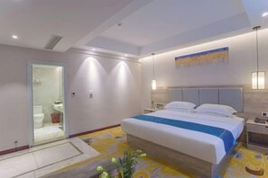 A modern hotel room with a large bed, a bedside table, a nightstand, a wall-mounted lamp, and a painting above the bed. - Tianshun Bo'erman Hotel (Zhongshan)