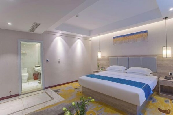 A modern hotel room with a large bed, a bedside table, a nightstand, a wall-mounted lamp, and a painting above the bed. - Tianshun Bo'erman Hotel (Zhongshan)