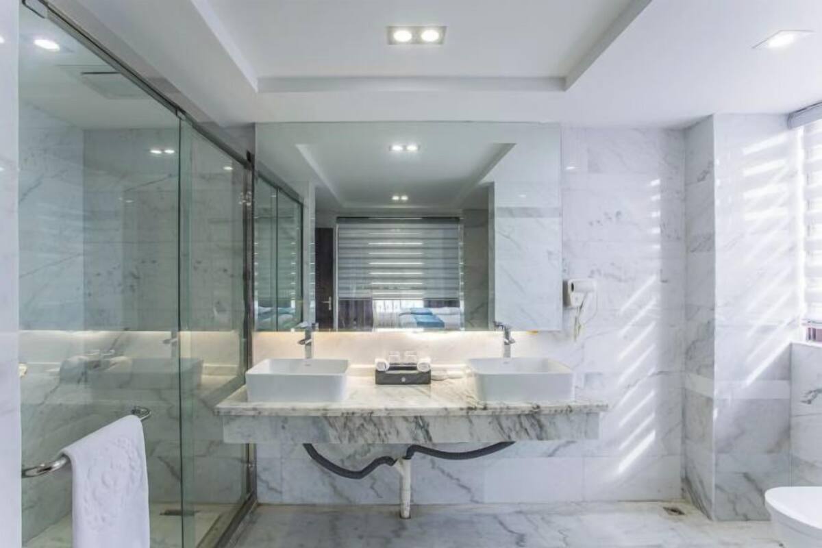 A modern bathroom with two sinks, a glass shower enclosure, and a marble floor.