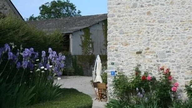 A stone building with a paved pathway leading to a wooden table and chairs. - Old farmhouse in Montchaton Orval sur sienne near Mont Saint Michel (Montchaton Orval sur sienne)