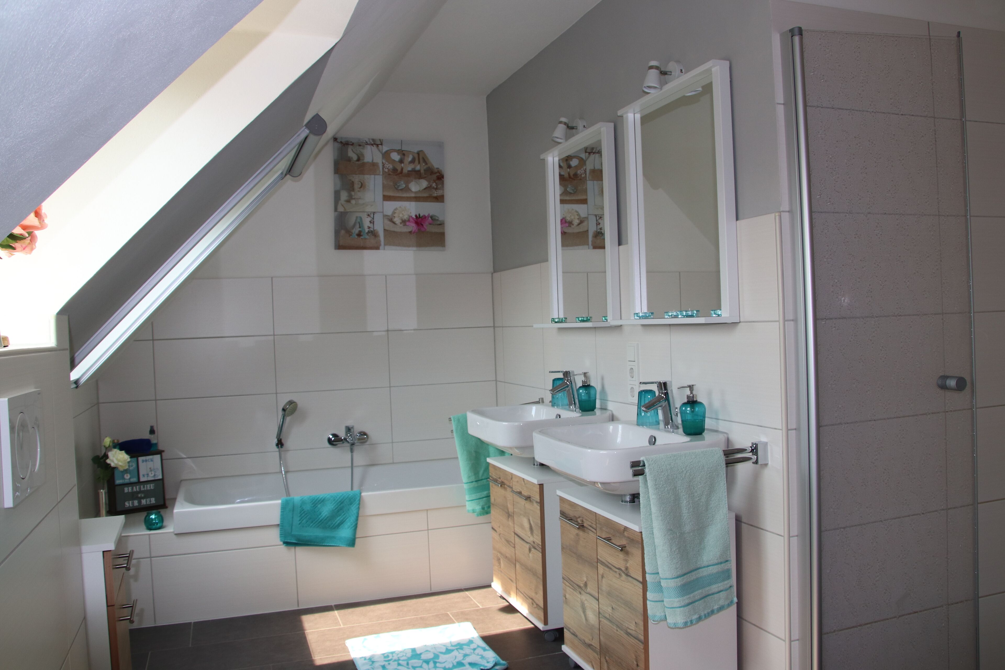 Un baño moderno con bañera, dos lavamanos, armarios de madera y un espejo grande.