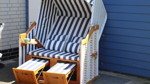 A striped beach chair with a matching umbrella, a small table, and a cup and saucer set. - Luxurious FH near the dike, sauna, fireplace, garden, beach chair (8 adults & baby) (Butjadingen)