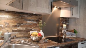 A modern kitchen with a wooden backsplash, stainless steel appliances, and a bowl of fruit on the counter. - Luxurious FH near the dike, sauna, fireplace, garden, beach chair (8 adults & baby) (Butjadingen)