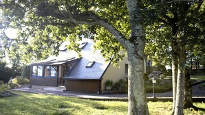 A house with a sloped roof, a front porch, and a well-maintained lawn. - Charming country home (Plogonnec)