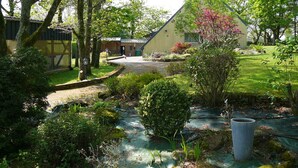A garden with a stone pathway leading to a building with a sloped roof. - Charming country home (Plogonnec)
