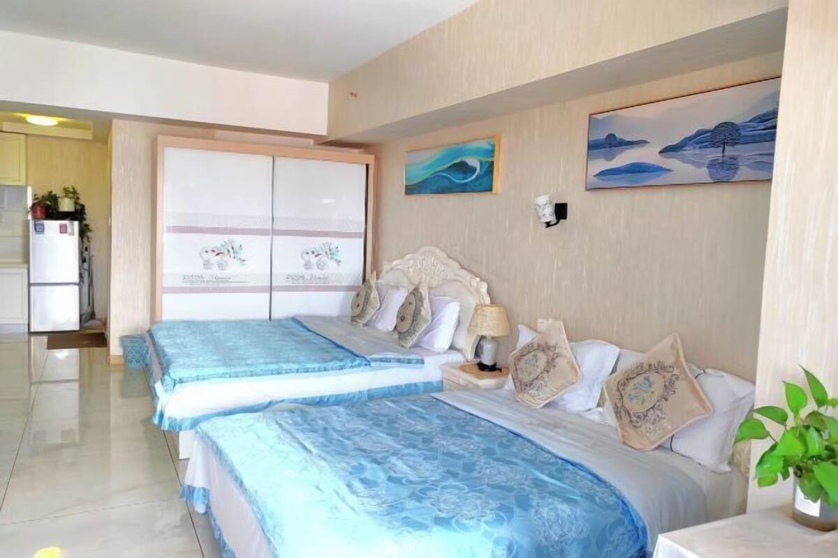 Habitación de hotel con dos camas, un ventanal grande y obras de arte en las paredes.